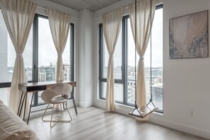 A modern room with large windows, a desk, a chair, and a city view. - Skyline Penthouse | 360° Views (Montreal)