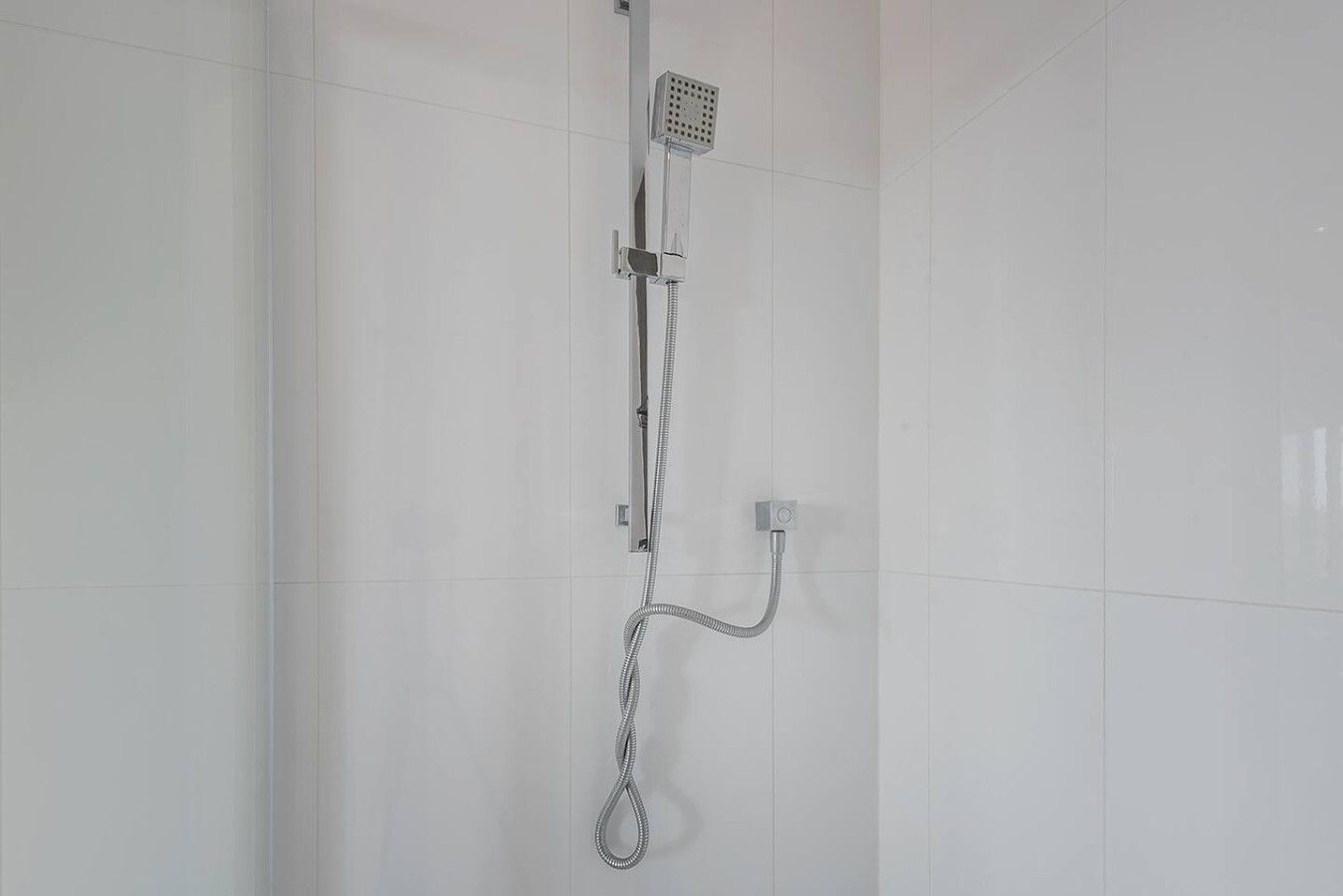A shower with a handheld showerhead and a fixed showerhead mounted on the wall.