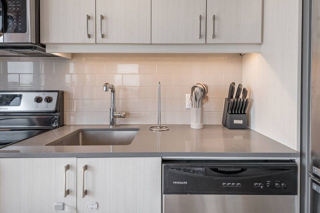 Una cocina moderna con electrodomésticos de acero inoxidable, un lavamanos doble y un lavavajillas.