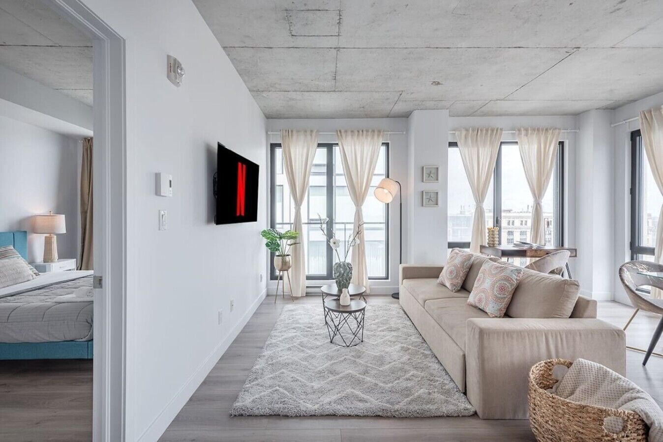 A modern living room with a sofa, a TV, and a dining area.