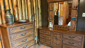 A wooden dresser with drawers and a mirror, placed against a bamboo wall. - Chalet Lumière Chalet Lumière (Rawdon)
