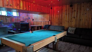 A pool table in a room with wooden walls and a couch. - Chalet Lumière Chalet Lumière (Rawdon)