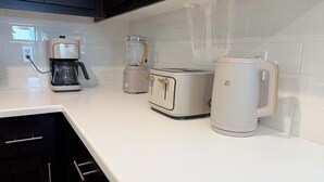 A kitchen with a coffee maker, a blender, a toaster, and a kettle on a white countertop. - Spacious 3-bedroom New house , Feel at home (Turlock)