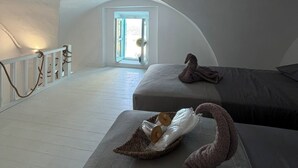 A high-ceilinged room with a large skylight, a white railing, and a bed with a blanket and a stuffed toy.