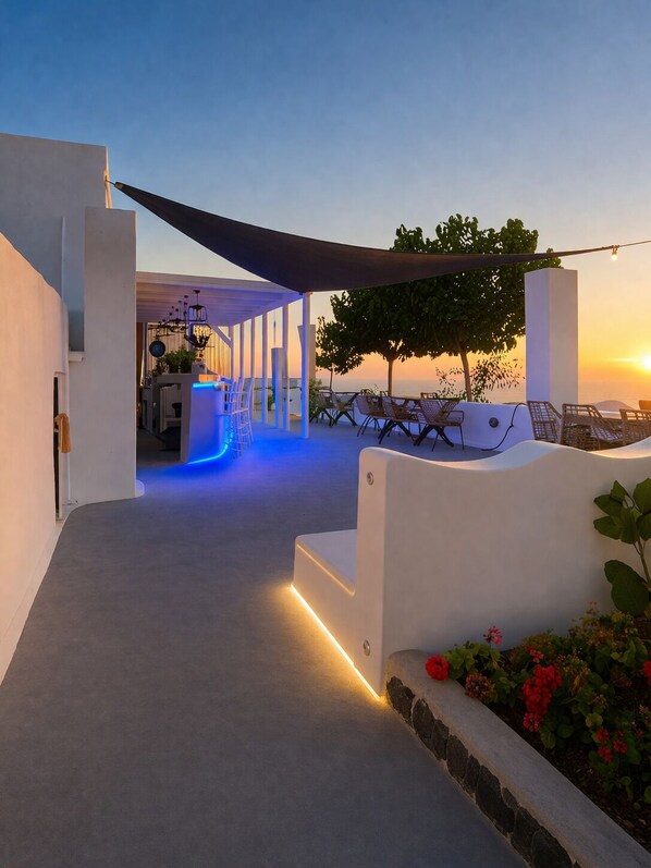 A modern outdoor patio area with a seating arrangement, a pathway leading to a covered area, and a view of the sunset.