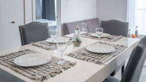 Une table à manger dressée avec des assiettes, des verres et des couverts, entourée de chaises.