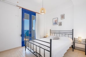 Une chambre à coucher comprenant un lit, une table de chevet, une lampe fixée au mur et une porte donnant sur un balcon.