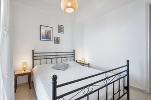 Een slaapkamer met een bed, nachtkastjes, wanddecoraties en een hanglamp.