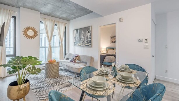 Ein modernes Wohnzimmer mit Essbereich, einer Couch, einem Couchtisch und einem großen Fenster.