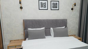 Een hotelkamer met een bed, nachtkastjes en twee ingelijste foto's aan de muur.