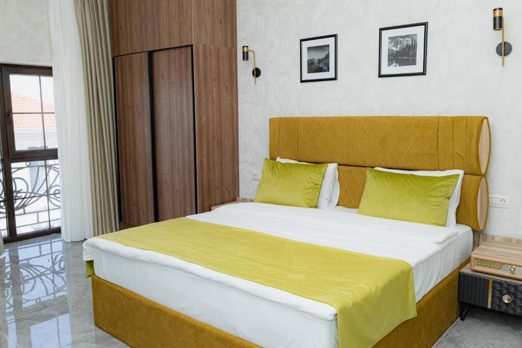 A hotel room with a bed, a wooden wardrobe, a nightstand, and a window with curtains.