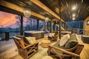 A wooden deck with a hot tub, seating area, and a view of the forest. - Glass Cabin Retreat w/ Hot Tub, Sauna + Epic Views (Morganton)