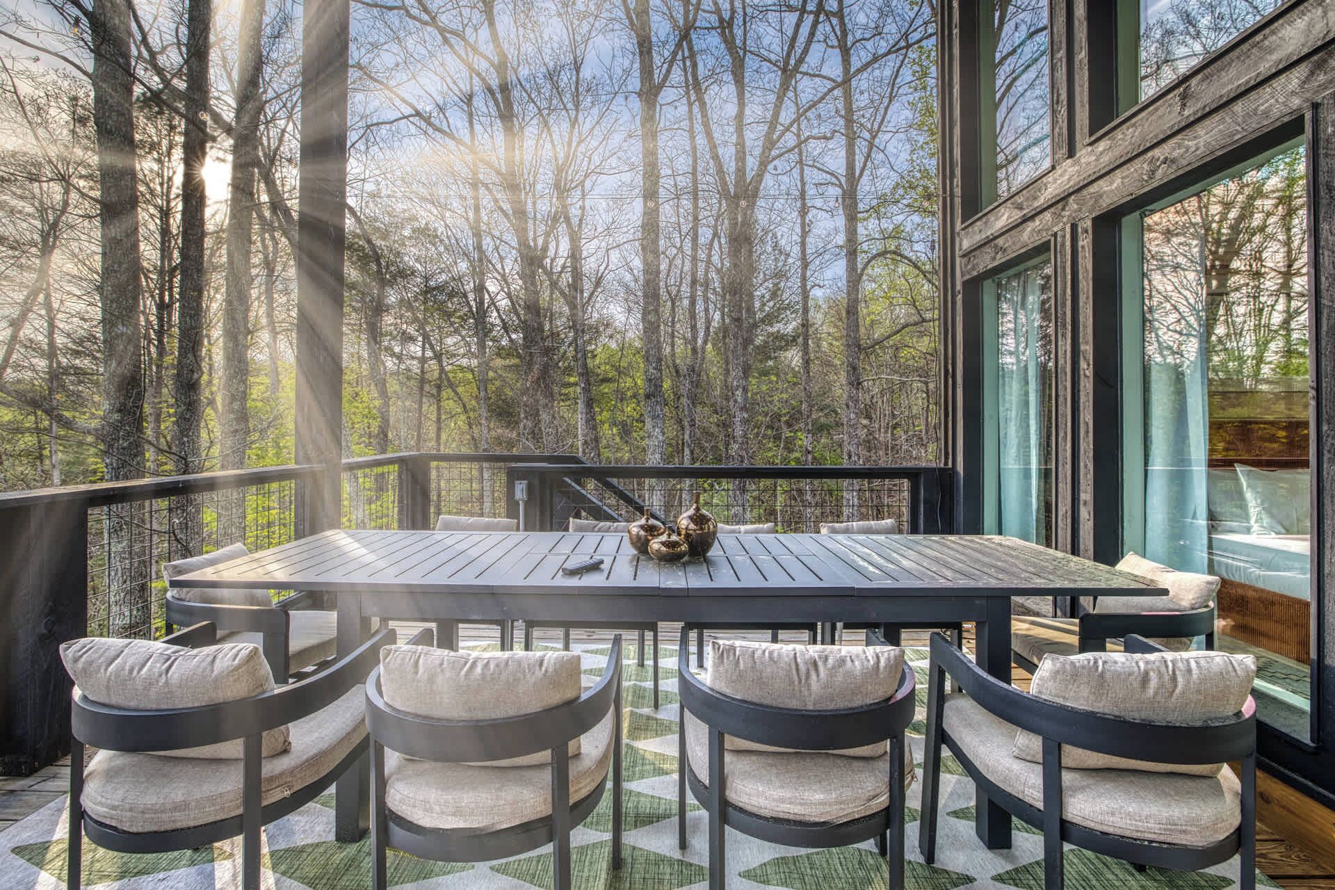 A deck with a table and chairs, overlooking a forest.