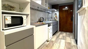 Une cuisine moderne avec des meubles blancs, un four à micro-ondes et un dosseret carrelé.