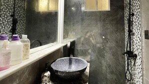 Une salle de bain avec un grand miroir, un lavabo noir, une douche et un mur carrelé.