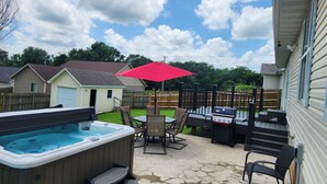 A backyard with a hot tub, patio furniture, and a barbecue grill.
