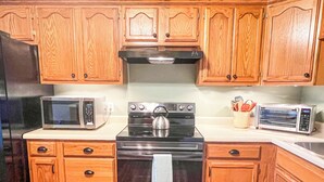 A kitchen with wooden cabinets, a microwave, an oven, and a toaster.