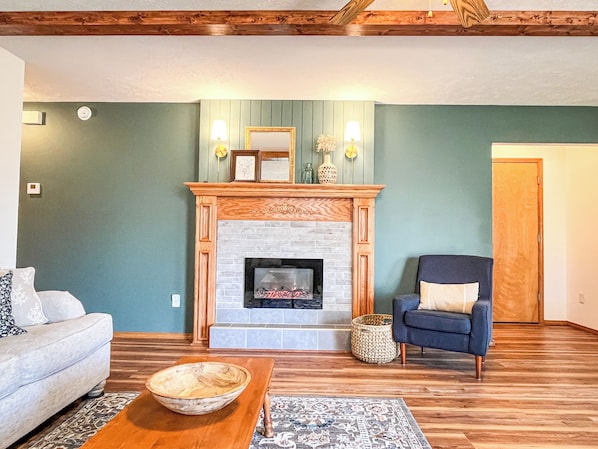 Una sala de estar con chimenea, un sofá, un sillón y una mesa de centro.