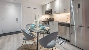 Una cocina moderna con electrodomésticos de acero inoxidable, una mesa de comedor de vidrio y sillas grises.