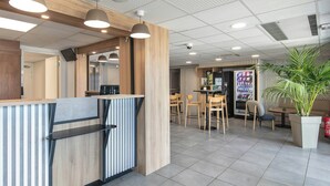 Een modern interieur met een receptiebalie, een zithoek, een automaat en een kamerplant.