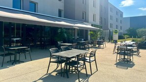 Een hotel met buiten zitplaatsen, een overdekt terras en een bordje dat de beschikbaarheid van een Bed en Breakfast aangeeft.