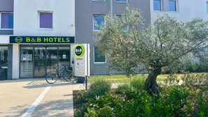 Een bed en ontbijfpand met een moderne gevel, een fiets voor de deur en een boom op de voorgrond.