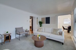 A modern living room with a white sofa, a round wooden coffee table, and a minimalist design. - Pet-Friendly 3BR • Game Room • Near Hospitals (South Euclid)