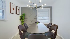 Ein Konferenzraum mit rundem Tisch, vier Stühlen, einer Topfpflanze und einer modernen Chandelierleuchtre.