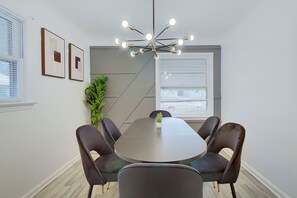A conference room with a round table, four chairs, a potted plant, and a modern chandelier. - Pet-Friendly 3BR • Game Room • Near Hospitals (South Euclid)