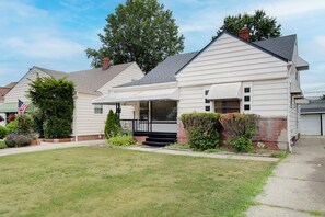 A two-story house with a front porch, a brick chimney, and a well-maintained lawn. - Pet-Friendly 3BR • Game Room • Near Hospitals (South Euclid)