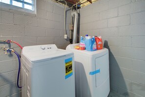 A laundry room with two front-loading washing machines, a hose, and detergent bottles. - Pet-Friendly 3BR • Game Room • Near Hospitals (South Euclid)