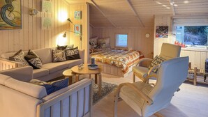 Et hyggeligt rum med sofa, stol, seng og et lille bord.
