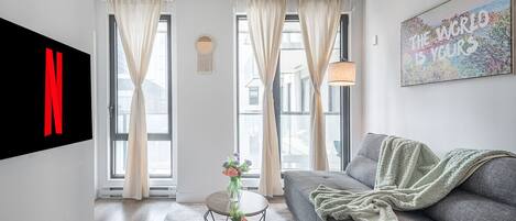 A modern living room with a grey sofa, a coffee table, and a TV mounted on the wall.