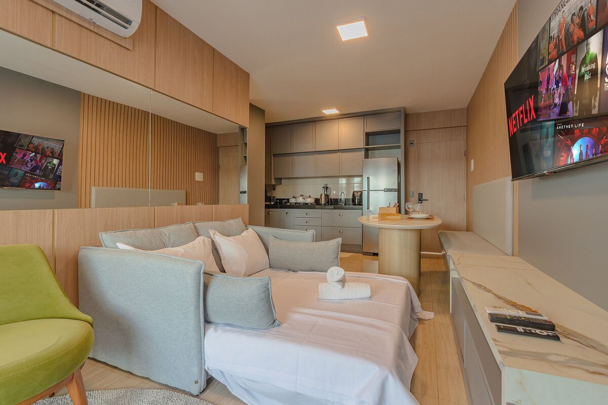 Une chambre d’hôtel moderne équipée d’un canapé, d’un lit, d’un petit coin cuisine et d’un téléviseur permettant d’accéder au contenu de Netflix.