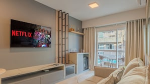 Ein modernes Wohnzimmer mit großem Flachbildfernseher, einer Couch, einem Couchtisch und einem Kamin.