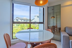 Una habitación moderna con un ventanal grande, una mesa redonda de vidrio y un sofá.