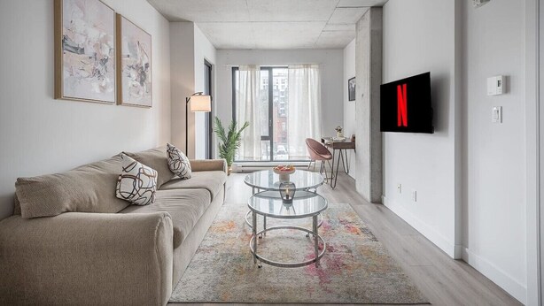 A modern living room with a sofa, coffee table, and TV. - Chic 2BR in Old Port • Walk to Everything (Montreal)
