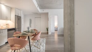 A modern kitchen with a dining area, wooden table, and pink chairs. - Chic 2BR in Old Port • Walk to Everything (Montreal)