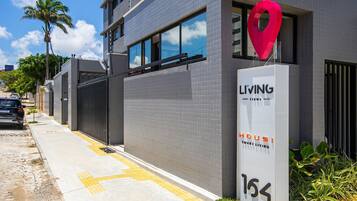 A modern building with a prominent red location marker, a gated entrance, and a clear sky.