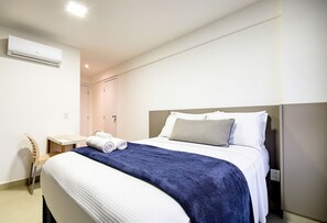 Ein Hotelzimmer mit einem Bett, einem Schreibtisch und einer Klimaanlage.