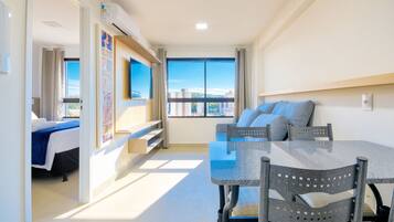 Un apartamento moderno con zona de comedor, un juego de sofás y un amplio ventanal con vistas a la ciudad.