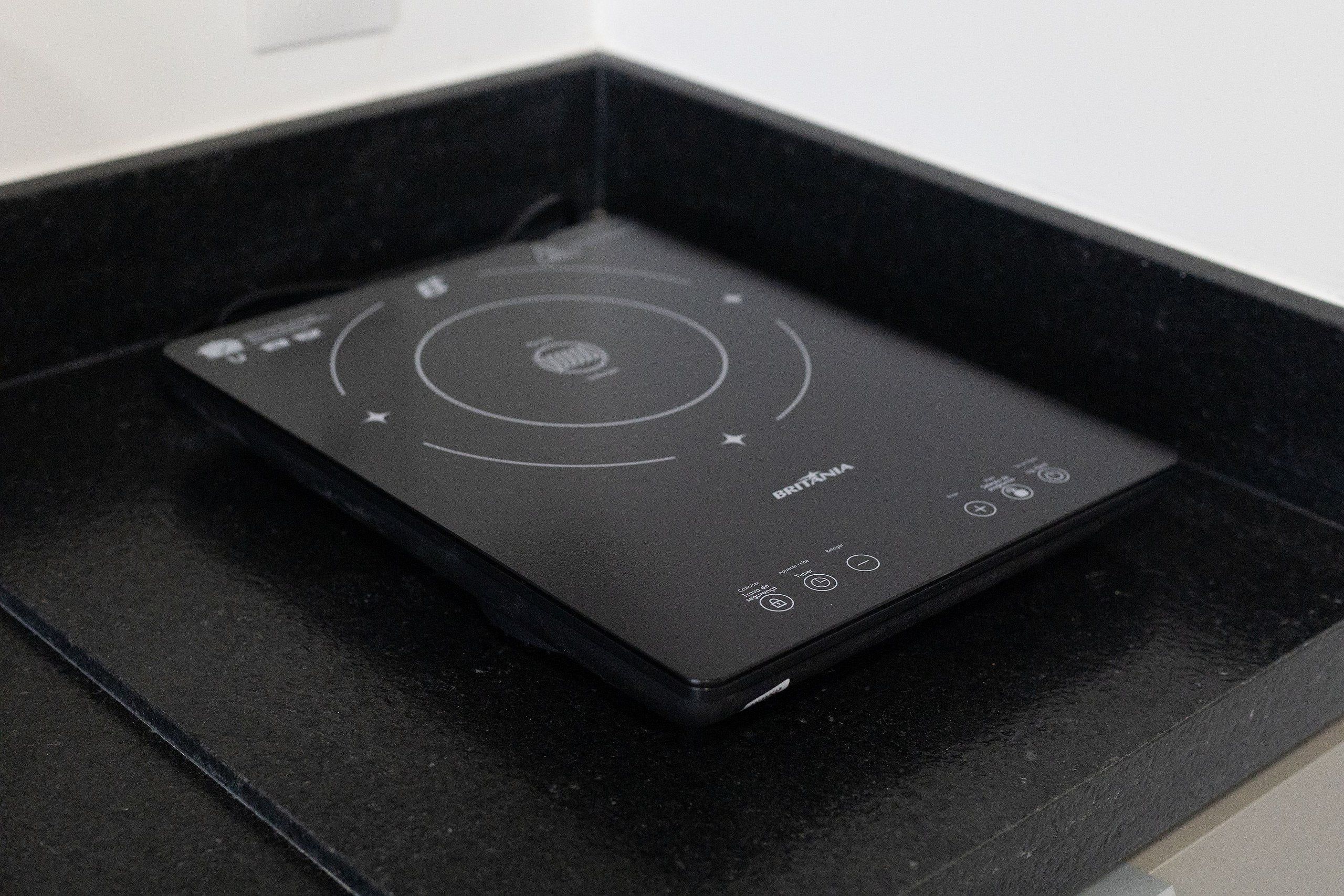 A black induction cooktop with a digital interface, control buttons, and a power switch.