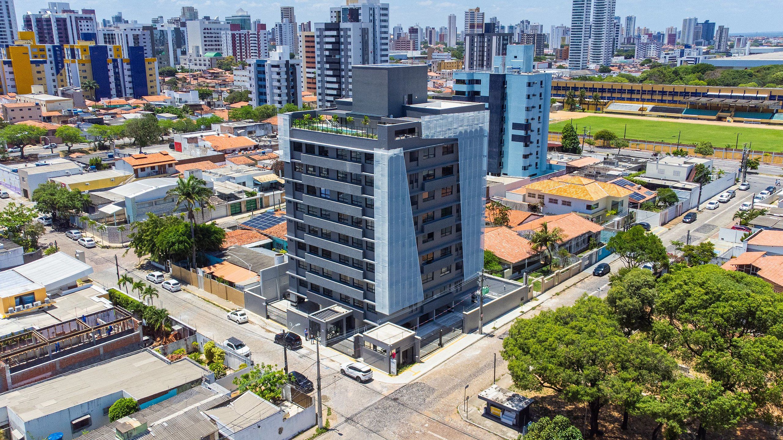 A high-rise building with multiple floors, surrounded by other buildings and greenery.