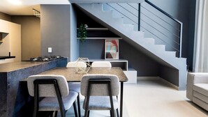 A modern kitchen with a dining area, a staircase, and a living room. - Living Tirol Housi Smart Living by Carpediem (Natal)
