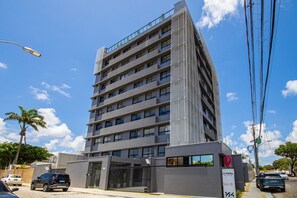 Un edificio de varios pisos con un diseño moderno, que cuenta con una entrada protegida por una reja y un letrero que indica que se trata de una propiedad residencial.