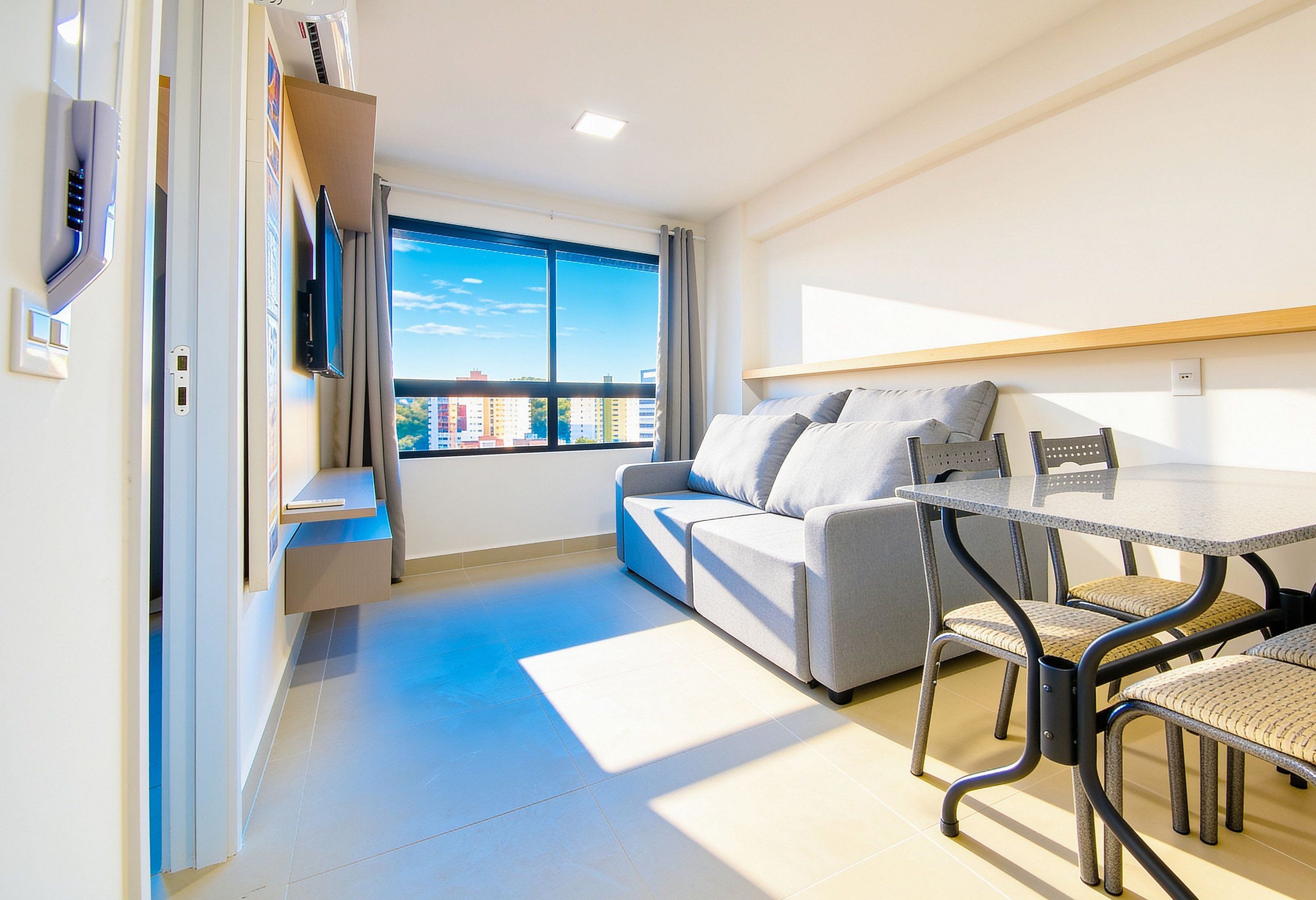 A modern room with a sofa, a dining table, and a TV mounted on the wall.