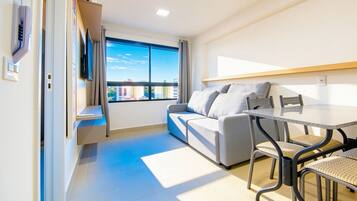 A modern room with a sofa, a dining table, and a TV mounted on the wall.