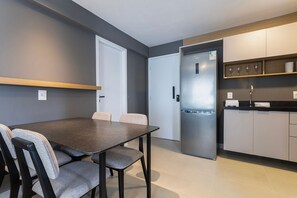 Eine moderne Küche mit integriertem Kühlschrank, einem Esstisch mit Stühlen und einer Arbeitsplatte mit Weingläsern.