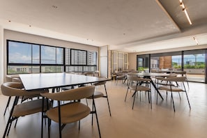 A modern conference room with large windows, multiple tables, and chairs. - Living Tirol Housi Smart Living by Carpediem (Natal)