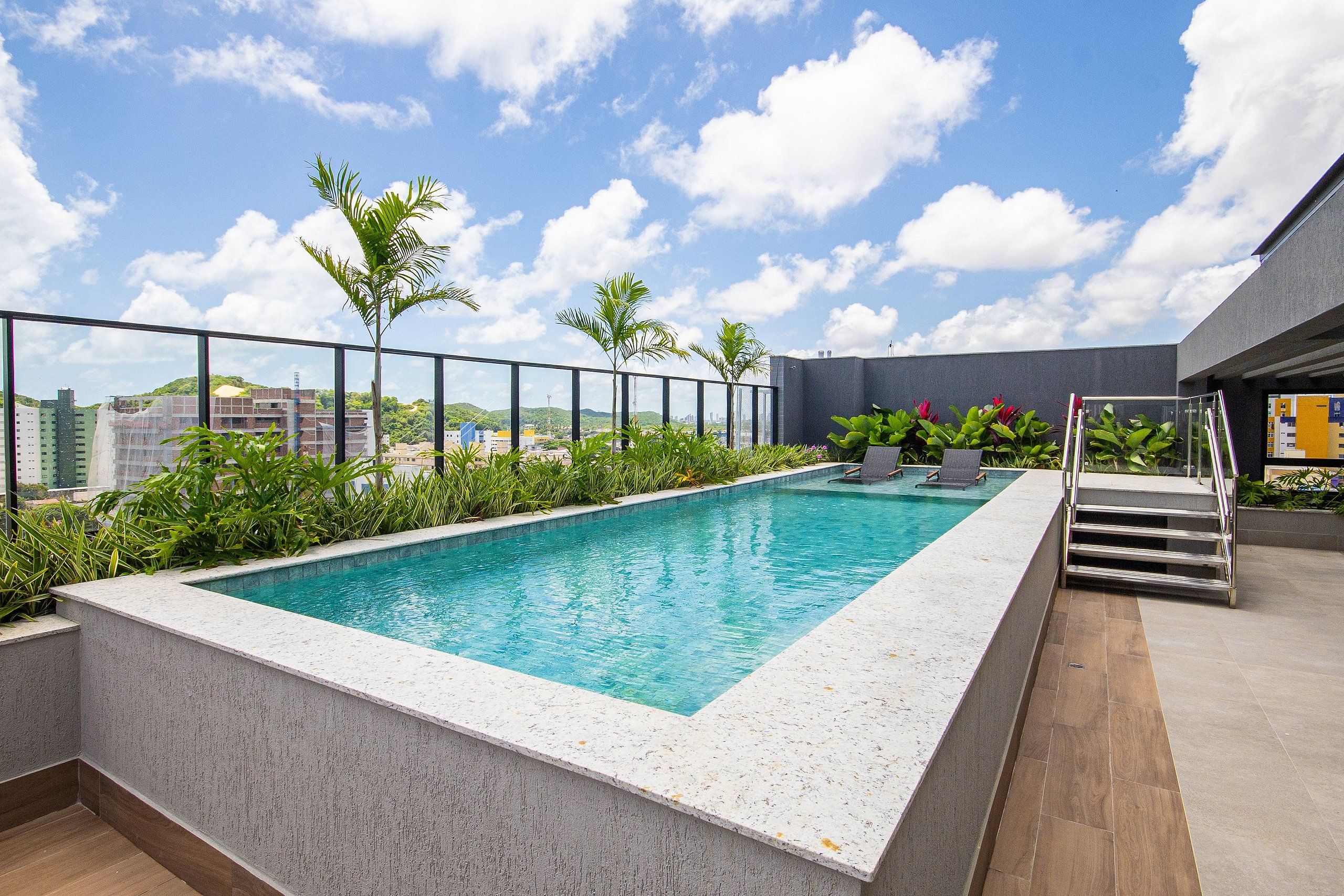 Ein Dachpool mit freiem Blick auf die Stadtlandschaft, umgeben von Grünflächen und einer modernen Gebäudestruktur.
